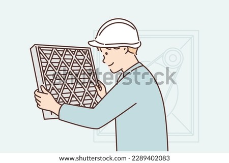 Man holding air conditioner replacement filter doing preventive maintenance or repairing HVAC equipment. Guy in work uniform and helmet changes filter on air conditioner to improve ventilation 