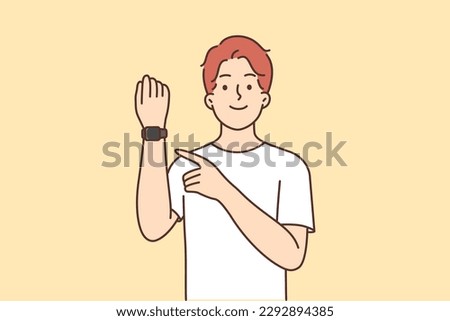 Man with fitness bracelet on hand points finger at tracker with gps function or measures steps and heart rate, smiling. Happy guy showing off new fitness bracelet for healthy lifestyle 
