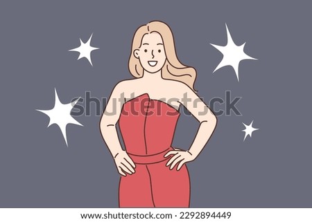 Celebrity woman poses for reporters standing in evening dress during film festival or statuette award ceremony. Girl movie star and celebrity stands on red carpet among flashes from cameras 