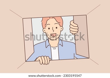 Man looks into cardboard box and looks inside with curiosity receiving order from courier from online store delivery service. Curious guy with smile inspects contents of box after moving