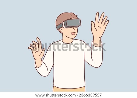 Boy wearing VR glasses enthusiastically uses new technology to immerse himself in virtual reality with 3d effect. Amazed kid plays VR game and raises hands to touch invisible objects