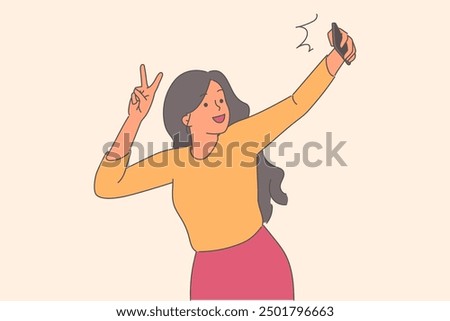 Woman takes selfie with mobile phone camera and shows victory gesture to capture happy moment. Girl blogger shoots selfie video for social network subscribers or broadcasts live on blog platform.