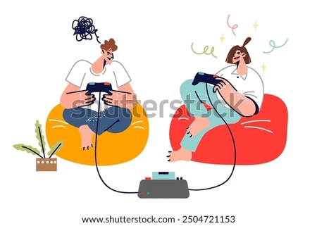 Teenagers play video games using joysticks and set-top box, sitting in soft chairs in living room. Man who loses video games feels embarrassed located near woman who wins and is into cyber sports.