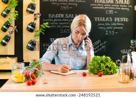 The owner of small restaurant writes order on paper