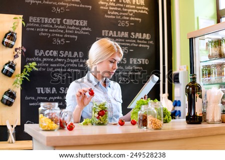 Small business owner reading the recipe on a digital tablet