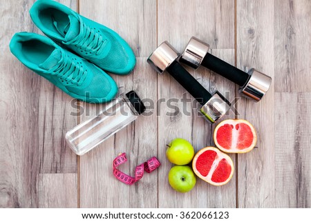 Fitness equipment. Healthy food. Sneakers, water,apple  on wooden background 商業照片 © 