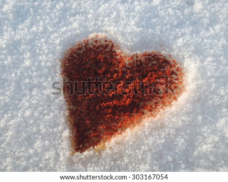 Sparkling strong love illustrated by a heart made of chili-powder on a snow background