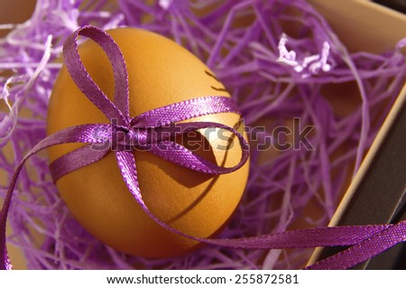 Easter egg with a bright lilac tape in a decorative lilac nest