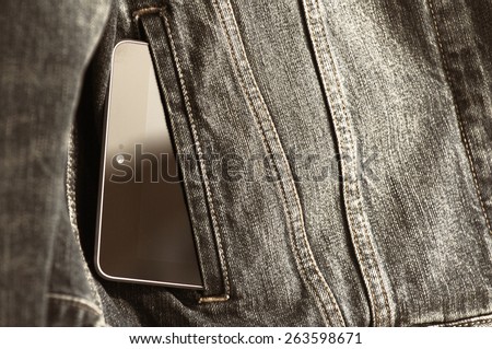The black tablet in a pocket of a jeans jacket