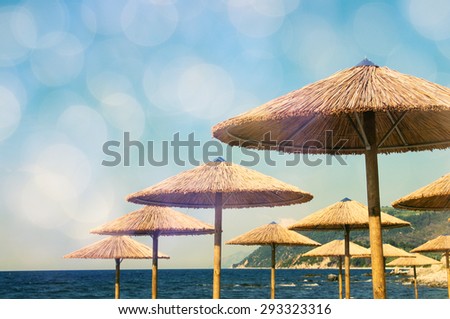 Beach bamboo umbrellas against the sea with bokeh. Sea summer landscape in vintage tones