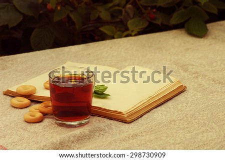 Tea in a glass mug, bagels and the open book with a mint leaflet on a linen cloth
