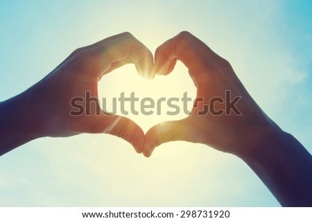 Photo of Female hands in the form of heart against the sky pass sun beams. Hands in shape of love heart