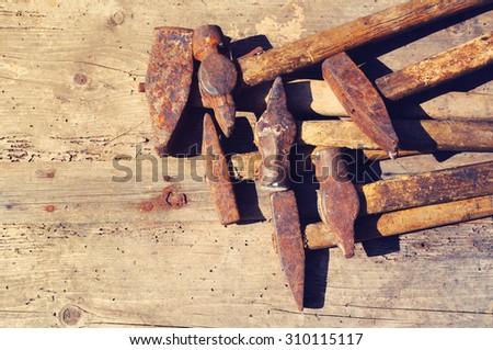 Old rusty hammers on a textural wooden surface. Collection of old hammers. Old tools