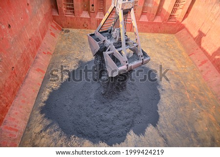 Loading of iron ore concentrate by steel grab inside cargo hold Foto d'archivio © 