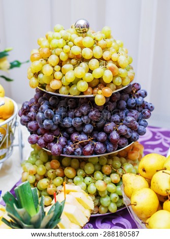 Banquet table served with delicious food. Fresh grapes and pears on the dish. Fruit dessert