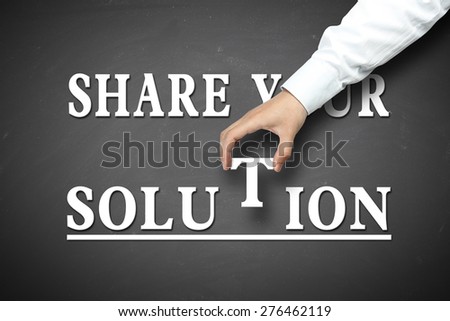 Share your Solution concept with businessman hand holding against blackboard background.