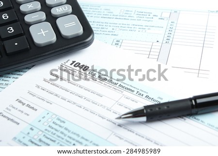 Tax form business financial concept with a pen and a calculator aside.