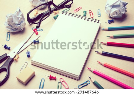 School supplies and blank notebook on the wood desk background.