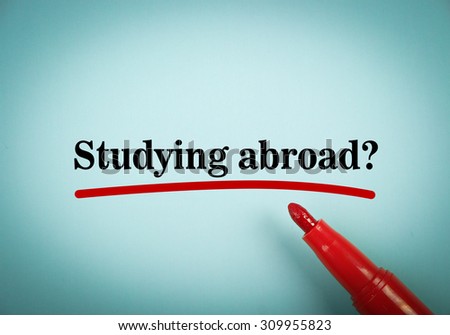 Text Studying Abroad with red underline and red marker aside on the blue background.