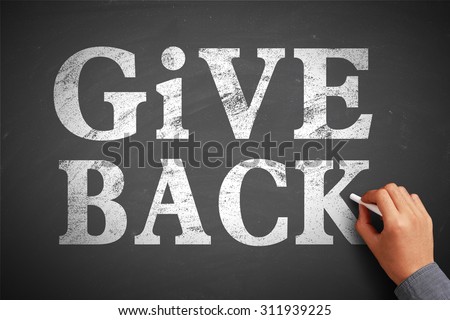 Hand with chalk is writing the concept of Give Back on the blackboard.