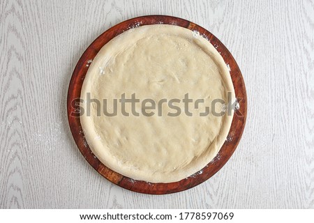Pizza dough, 2nd step of spreading the pizza dough on wooden board isolated on gray background. (How to make Pizza?) The basics of pizza making process, top view