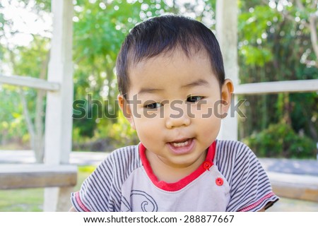 little boy in the spring or summer park sitting on the grass in sunshine day