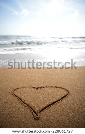 A heart drawn in the sand at the waters edge.