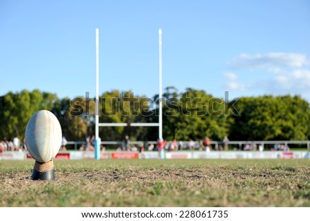 Football ready to be kicked between a set of goal posts on a sporting field.
