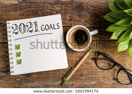 New year goals 2021 on desk. 2021 goals list with notebook, coffee cup, plant on wooden table. Resolutions, plan, goals, checklist, idea concept. New Year 2021 template, copy space