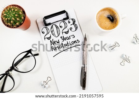 New year resolutions 2023 on desk. 2023 resolutions list with notebook, coffee cup on white table. Goals, resolutions, plan, action, checklist concept. New Year 2023 card top view Foto d'archivio © 