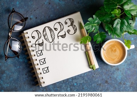New year resolutions 2023 on desk. 2023 resolutions list with notebook, coffee cup on table. Goals, resolutions, plan, action, checklist concept. New Year 2023 template, copy space Foto d'archivio © 