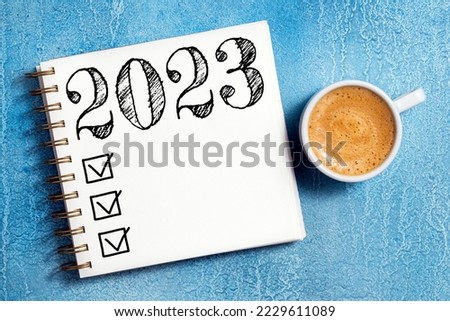 New year resolutions 2023 on desk. 2023 resolutions list with notebook, coffee cup on table. Goals, resolutions, plan, action, checklist concept. New Year 2023 template, copy space Foto d'archivio © 