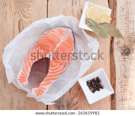 Raw salmon steak red fish and spices on wooden table