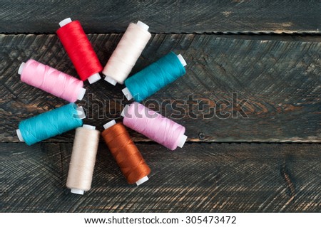 Spools of thread on old wooden background. Sewing accessories. Top view
