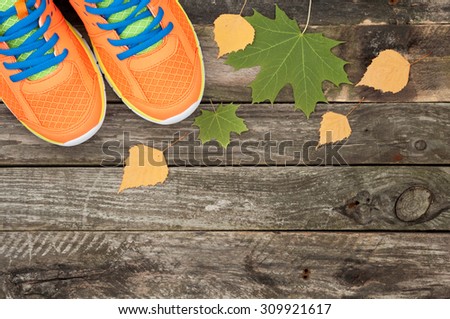 Sport shoes and autumn leaves on the old wooden background. Top view sport equipment. Autumn sports outdoors. Top view