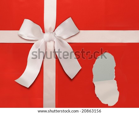Red holiday wrapping paper with white bow. Paper is ripped to reveal area for copy or your own gift.