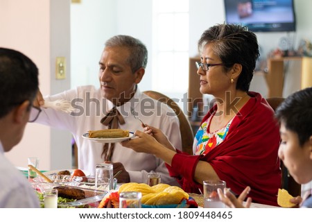 A couple of adults wearing typical mexican outfits sitting at a table on a mexican dinner eating typical mexican food