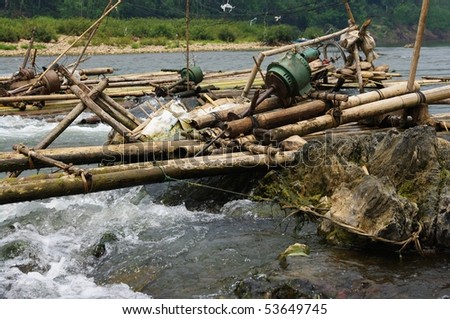 Improvised run-of-stream micro hydro electricity generation. Using boat propellers in rapids driving shafts to electric motors, all supported on bamboo scaffolding. Nam Ou River, Laos