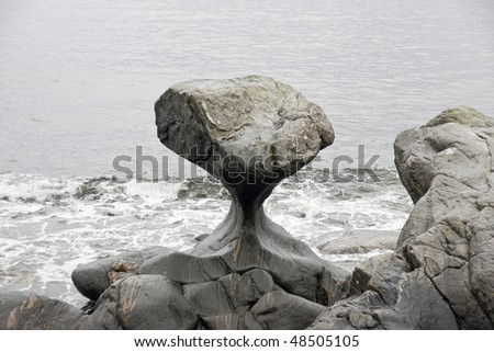 Unusual stone in Atlantic ocean coast. View on Kannesteinen and Kvalheimsvika. Over thousands of years, ocean waves have ground the rock to the special shape it has today.