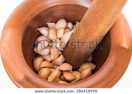 Crushing garlic using clay mortar and wood pestle