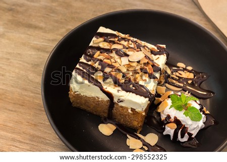 Carrot cake with fresh cream topping slice almond and chocolate sauce on a wooden background