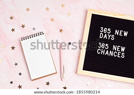 365 new days, 365 new chances. Letter board with motivational quote with notepad , pen and stars confetti. New year’s resolutions mockup. Flatlay, top view