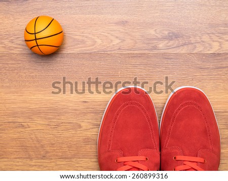 Pair of red sneakers and basket ball on the wooden floor