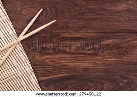 Chopsticks and bamboo napkin on a wooden brown background