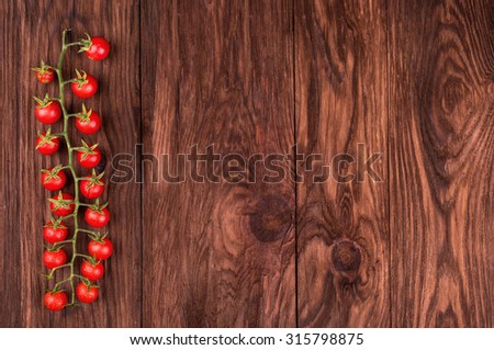 Sprig of fresh red cherry tomatoes on a wooden background for an inscription
