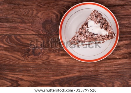 Piece of chocolate cake with cream in a bowl on a wooden table top view