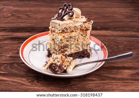 Piece of cake with chocolate and cream on a plate with broken pieces in a spoon