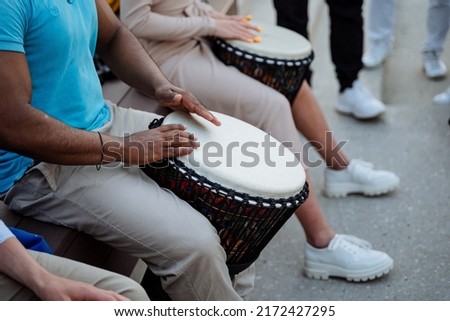 A strong muscular guy drums on a djemba, a street musician, drummers beat the rhythm of jazz in public, hands play on percussion. High quality photo Сток-фото © 