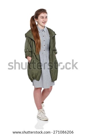 Full length portrait of beautiful young girl looking away smiling while standing over white background