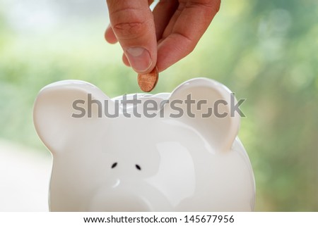 Piggy bank being loaded. Piggy Bank, Hand and Coin.